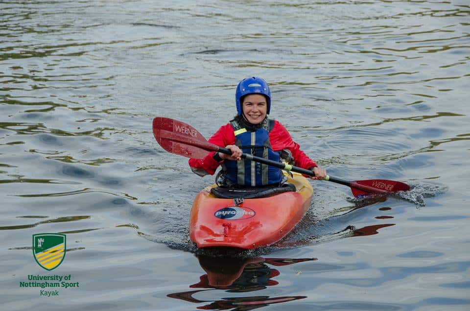 Me in a orange kayak on a lake, in a old boat and gear.